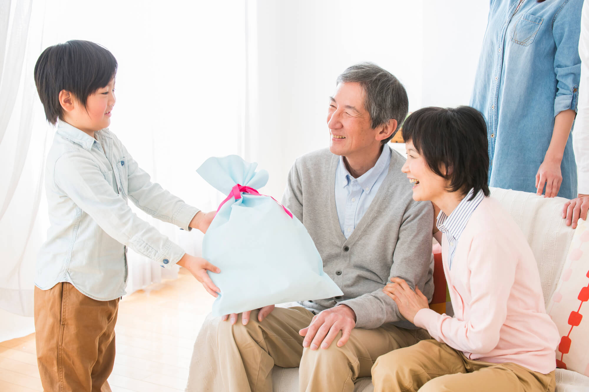 孫から祖父母へプレゼントを渡す家族の温かいシーン